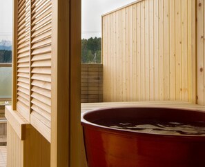 Relax in a sauna with a central hot tub, surrounded by a serene mountain view.