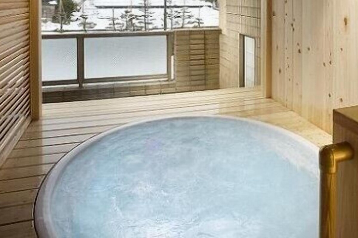 A wooden sauna with a large, round, empty bathtub.