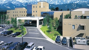 A modern building with a parking lot and a mountain backdrop. - Tsurugi Koizuki (Kamiichi)