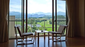 A room with two chairs and a small table, large windows with a view of mountains and greenery. - Tsurugi Koizuki (Kamiichi)