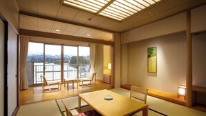 A traditional Japanese-style room with tatami flooring, a low table, and a view of a mountain landscape through large windows. - Tsurugi Koizuki (Kamiichi)