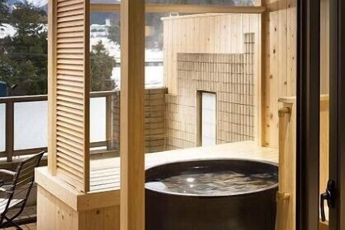 A traditional wooden bathhouse with a hot tub, wooden walls, and a view of the surrounding area.