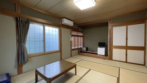 A traditional Japanese room with tatami flooring, a low wooden table, sliding doors, and a television. - Hotel Sejour mint (Hakuba)