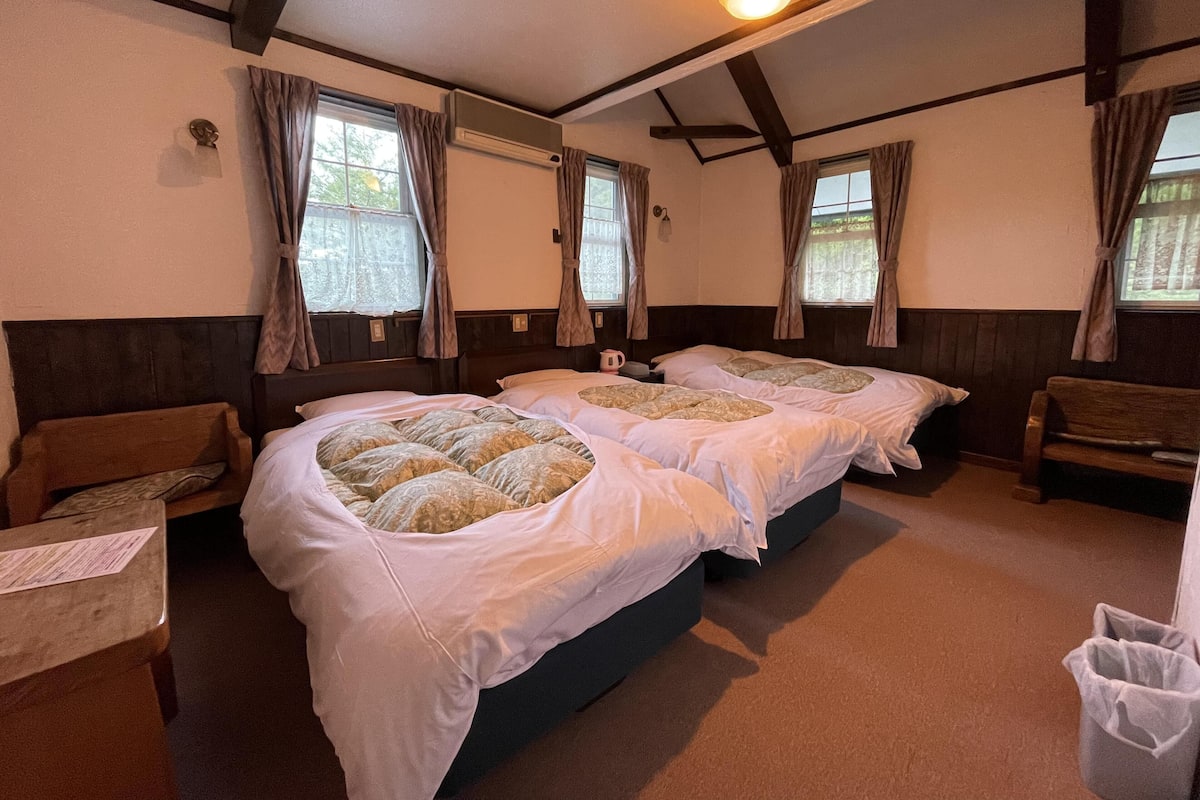A hotel room with four beds, wooden headboards, and a ceiling fan.