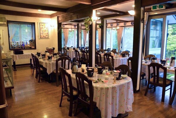 Un restaurante con varias mesas redondas, cada una dispuesta con sillas, platos y cubiertos.