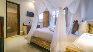Une chambre à coucher avec un lit à baldaquin, un téléviseur fixé au mur et une vue sur l’extérieur.
