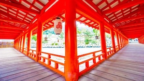 A covered wooden walkway with red pillars and a view of a garden. - Hiroshima Capsule Hotel & Sauna New Japan EX - Caters to Men (Hiroshima)