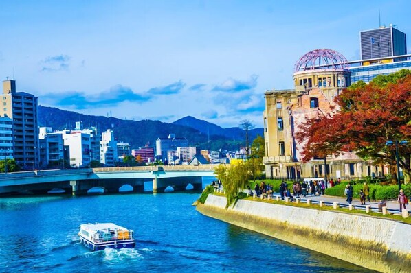 Un río con un bote, un puente y edificios, incluyendo una estructura histórica con una cúpula.