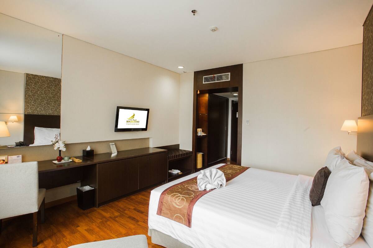 Een hotelkamer met een bed, een bureau, een spiegel en een televisie.