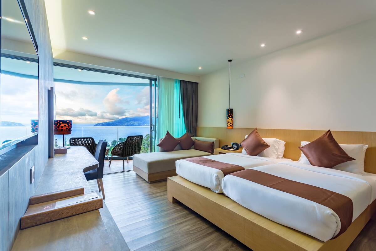Una habitación de hotel moderna con una cama grande, un escritorio y vistas al mar.