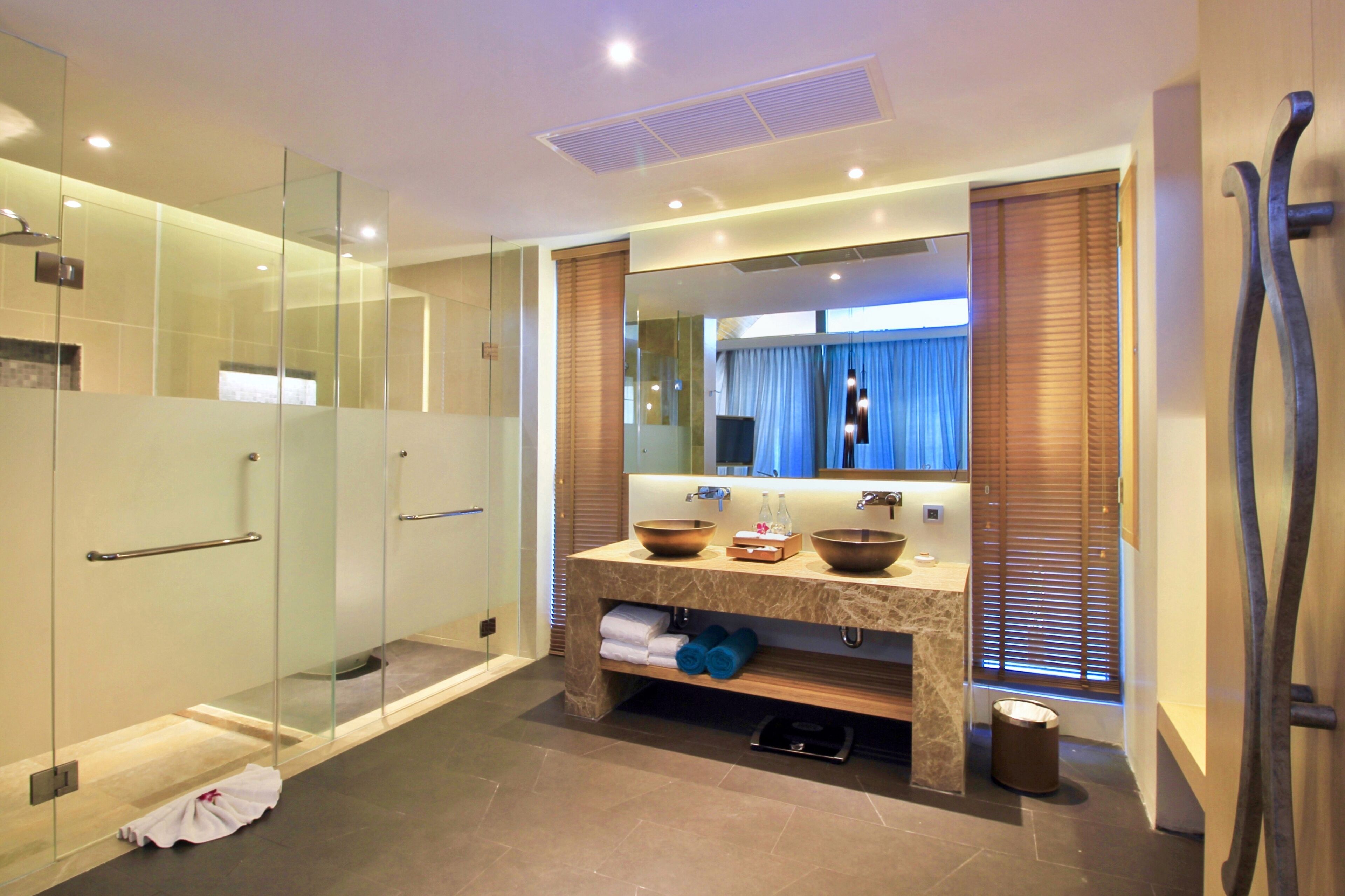 A modern bathroom with a glass-enclosed shower, a marble vanity with a large mirror, and a built-in sink.