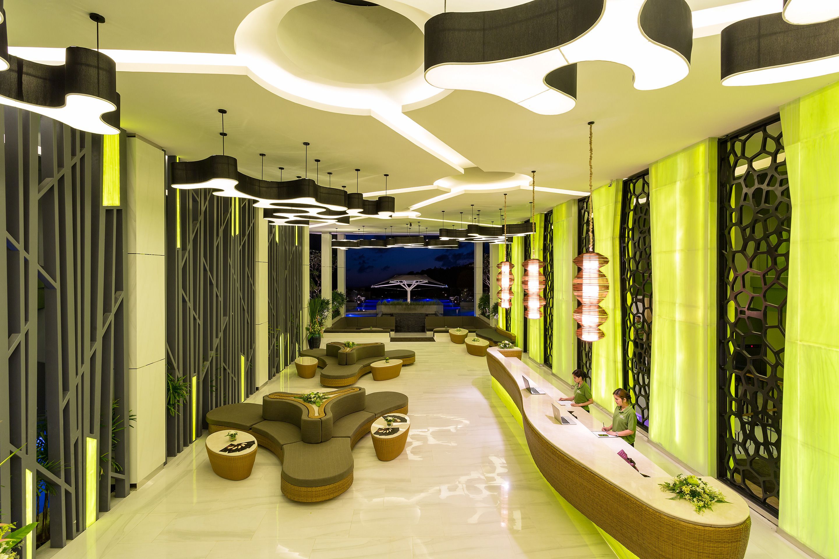 A modern lobby with a reception desk, seating areas, and a decorative ceiling.