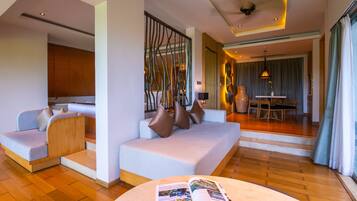 A modern hotel room with a sofa, a dining area, and a magazine on a table.