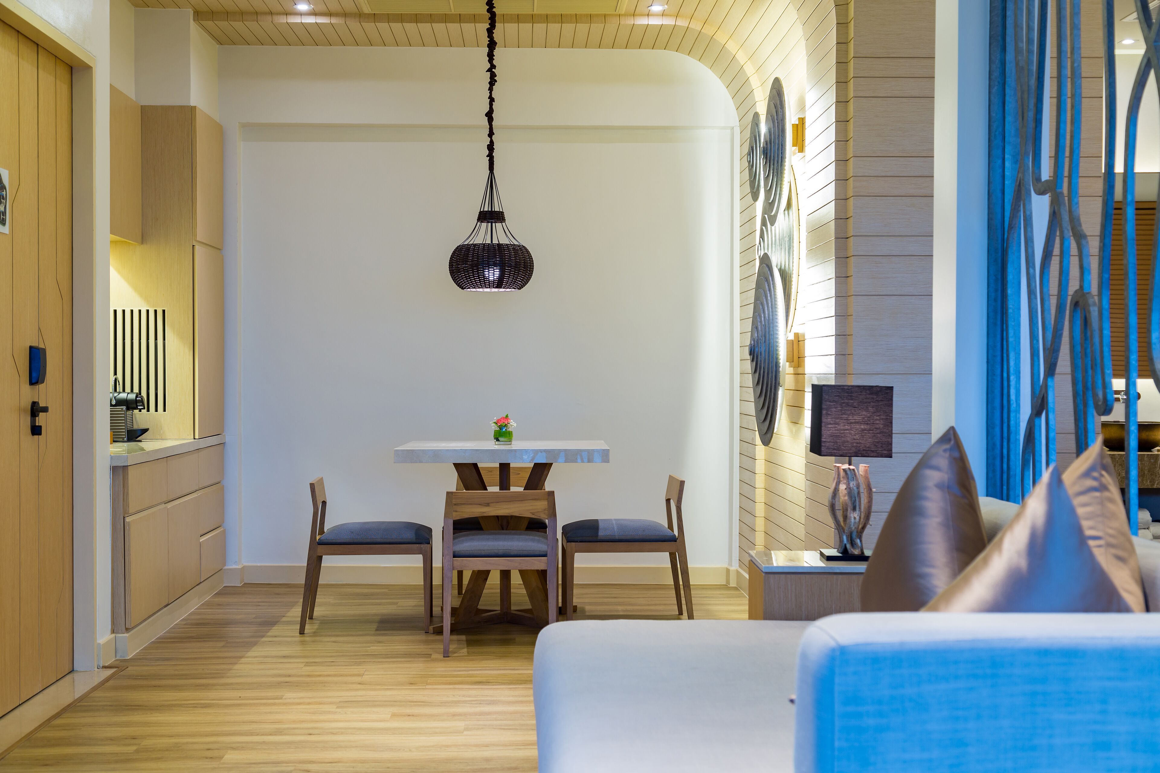 A modern kitchen with wooden cabinets, a dining table with chairs, and a hanging pendant light.