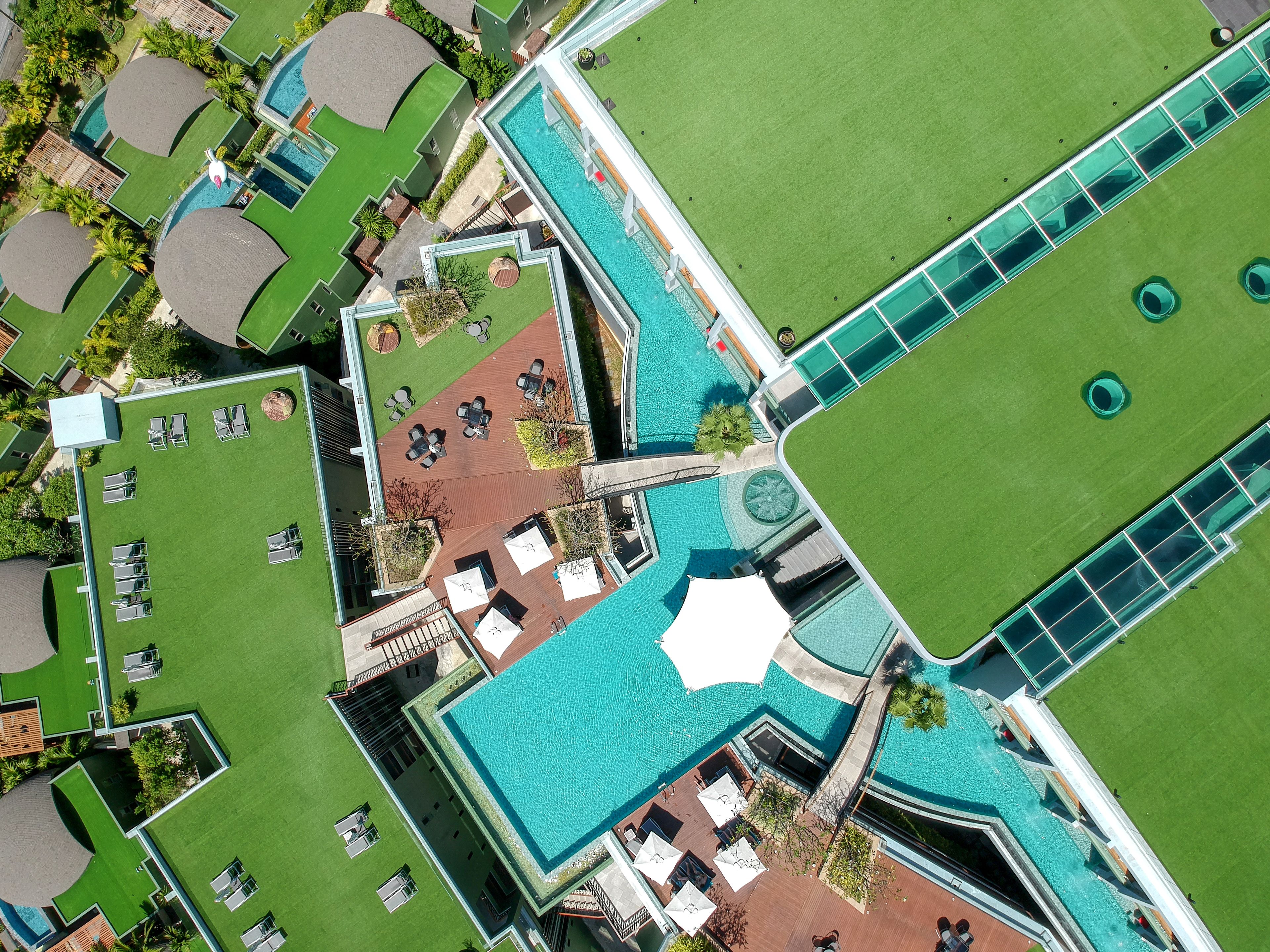 An aerial view of a resort with multiple swimming pools, green lawns, and outdoor seating areas.