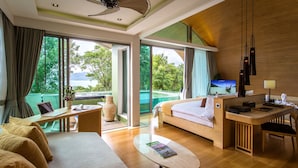 Een moderne hotelkamer met een groot bed, een bureau, een laptop en een televisie. Er is een balkon met uitzicht op de omgeving.