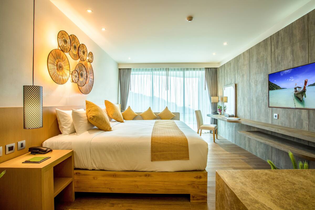 Una habitación de hotel moderna con una cama grande, un televisor de pantalla plana y vistas a un lago.