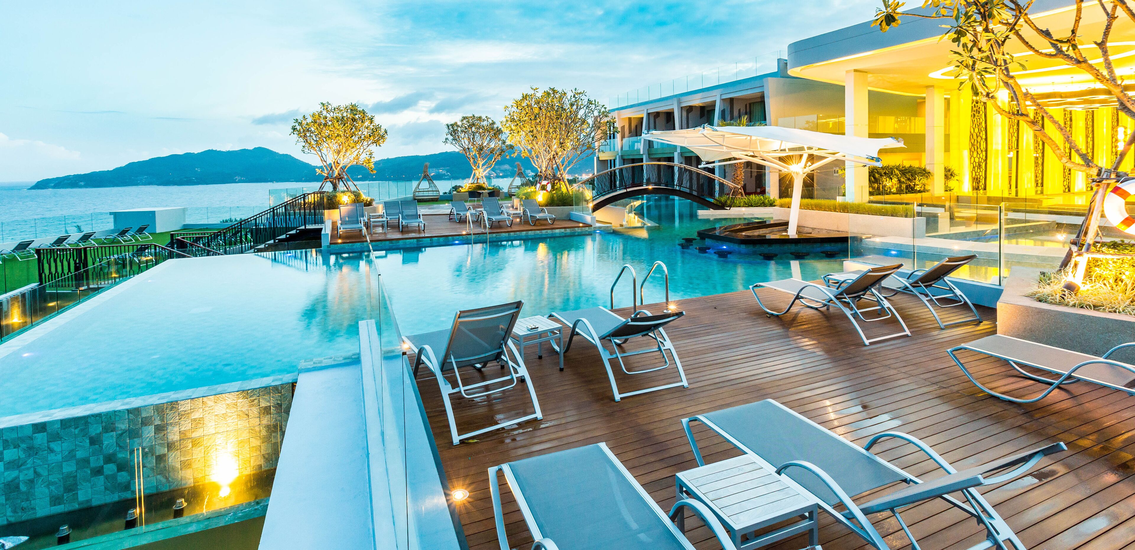 A poolside area with lounge chairs and a view of the sea.