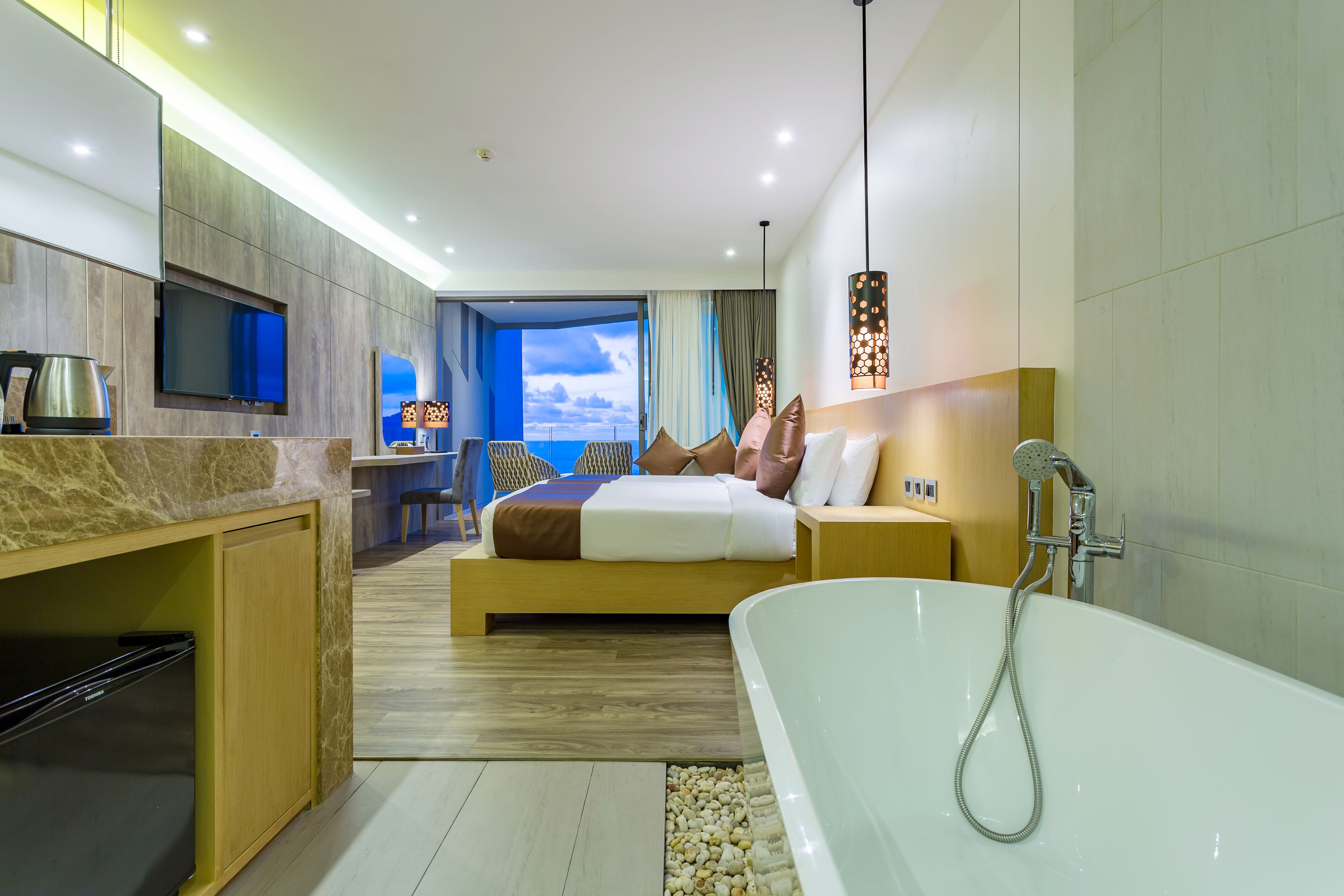 Une chambre d’hôtel moderne dotée d’un grand lit, d’une baignoire, d’une télévision et offrant une vue sur le ciel.