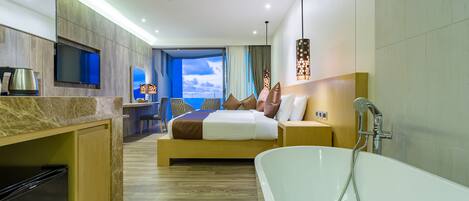 A modern hotel room with a large bed, a bathtub, a television, and a view of the sky.