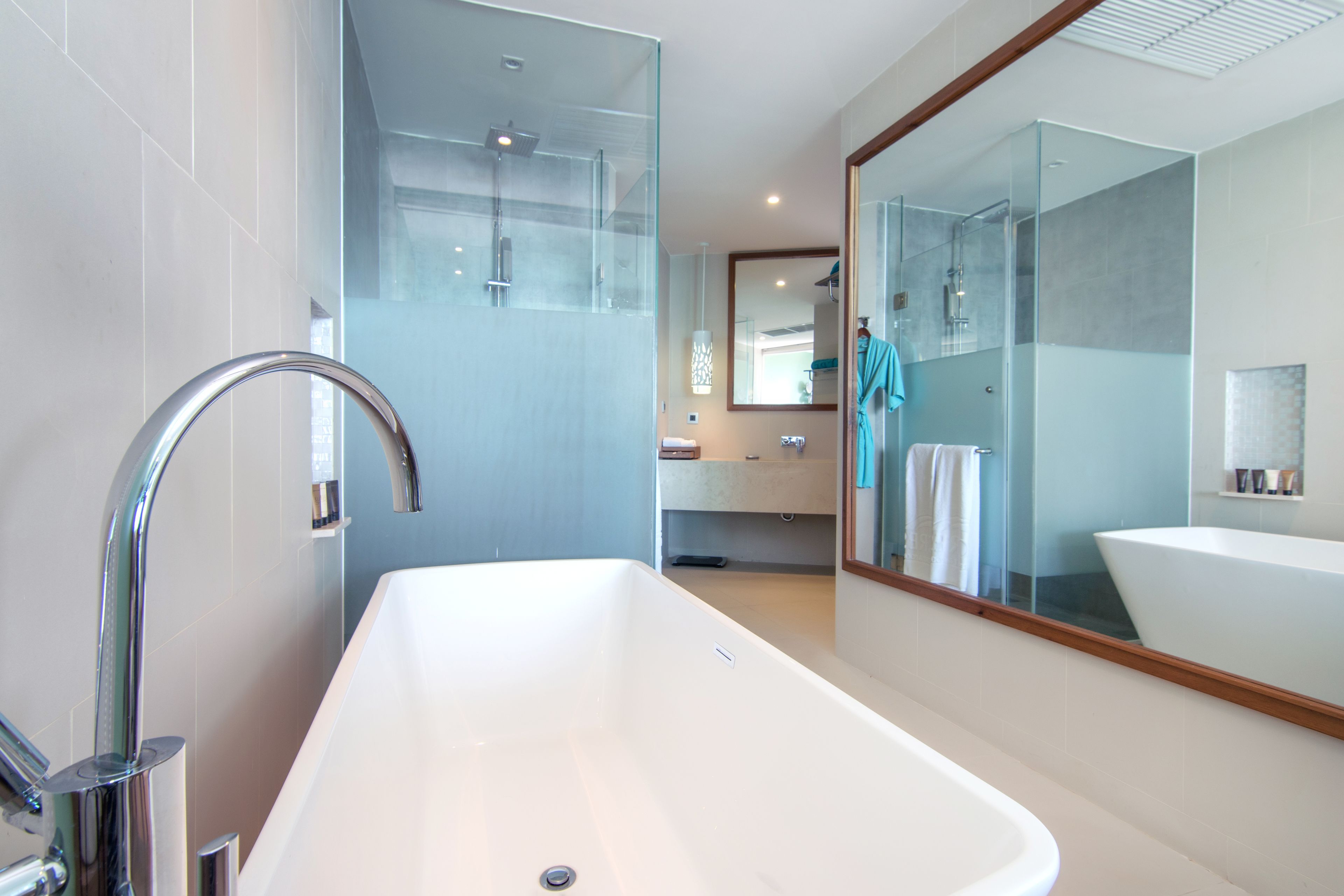 A modern bathroom with a large white bathtub, a glass-enclosed shower, and a large mirror reflecting the room.