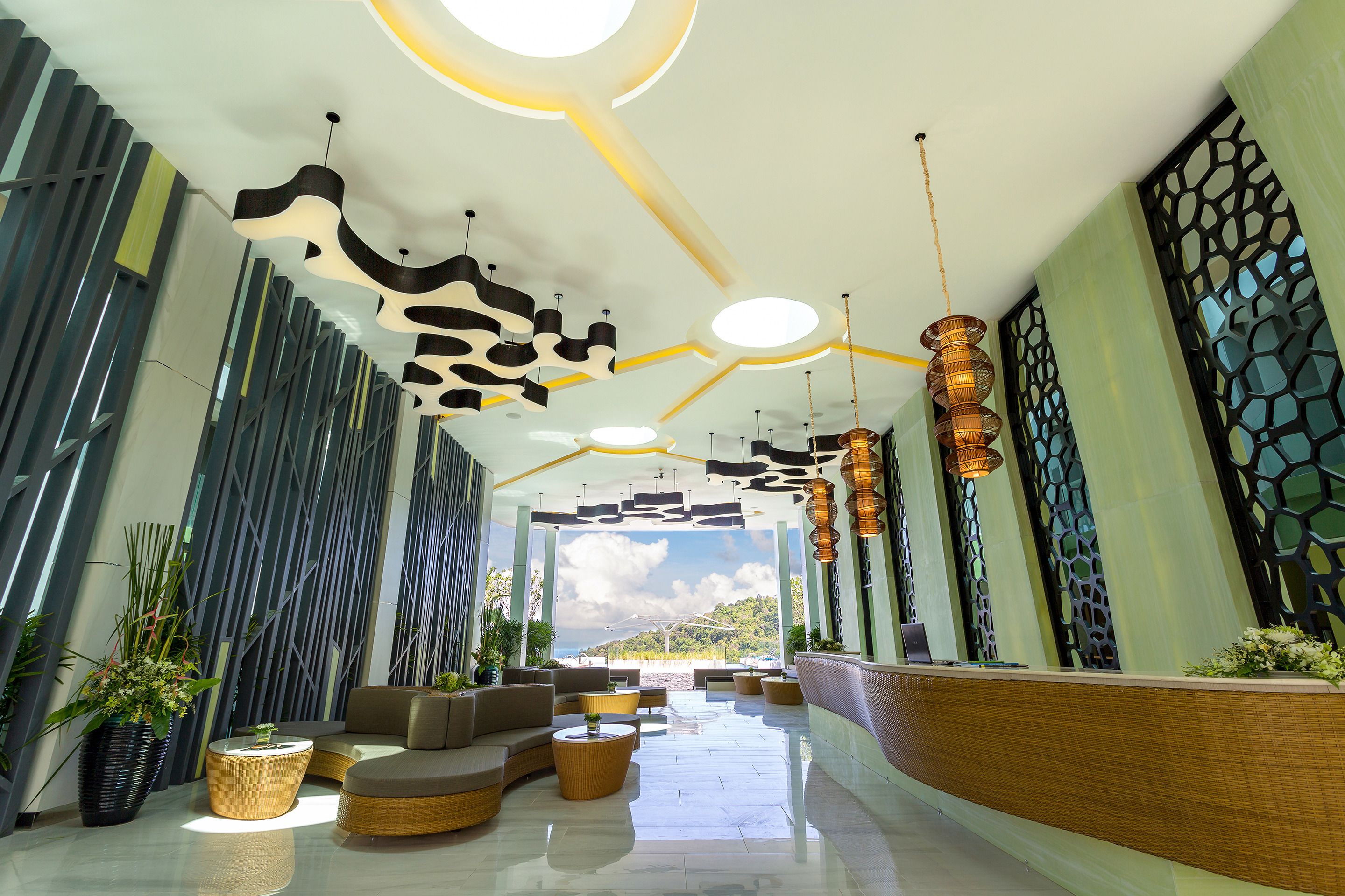 A modern lobby with a curved reception desk, comfortable seating areas, and a view of the beach.