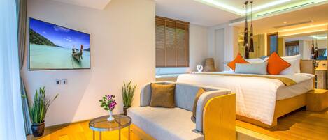 A modern hotel room with a large bed, a sofa, a small table, and a TV displaying a scenic view.