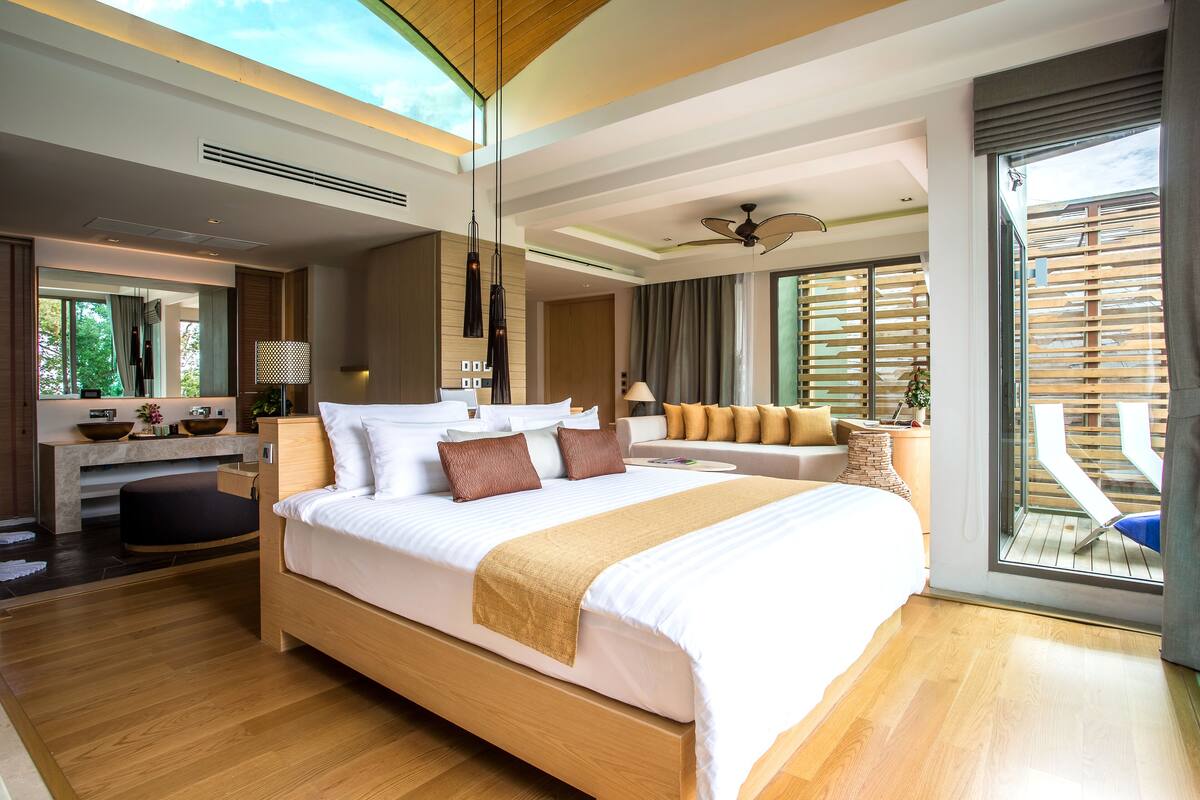 Una habitación de hotel moderna con una cama grande, un área de descanso con vistas y un balcón.