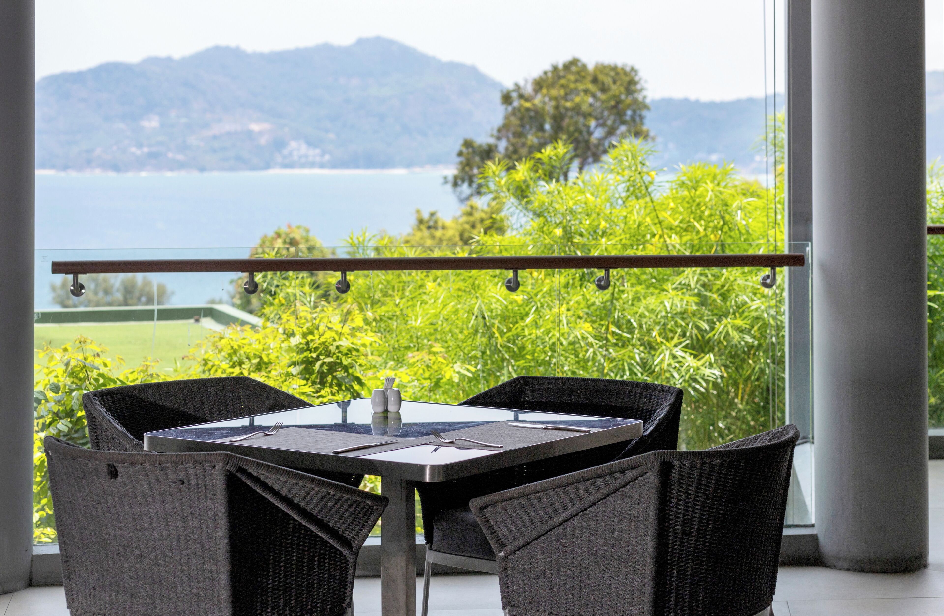 A dining area with a table and chairs, overlooking a scenic view of a body of water and greenery.