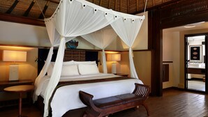 A four-poster canopy bed with a wooden bench, bedside tables, and a view of the room's interior. - The Villas at Novotel Lombok (Kuta)