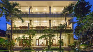 A multi-story building with a pool, outdoor seating, and lush greenery. - The Tunjung Ubud Retreat (Ubud)