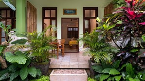 A covered entrance with a tiled floor, a wooden bench, and potted plants. - The Tunjung Ubud Retreat (Ubud)