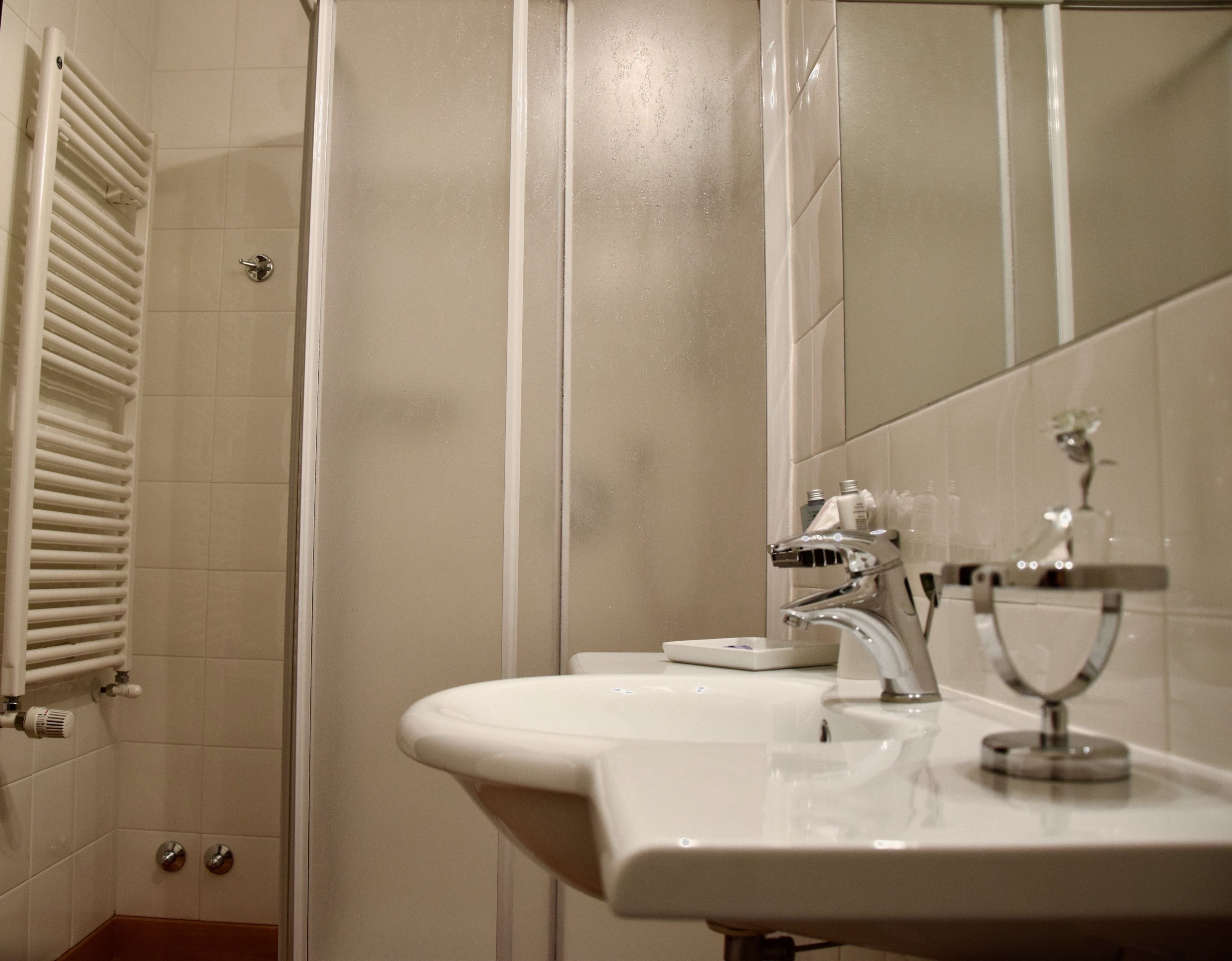 Une salle de bain avec un lavabo blanc, un miroir et une douche.