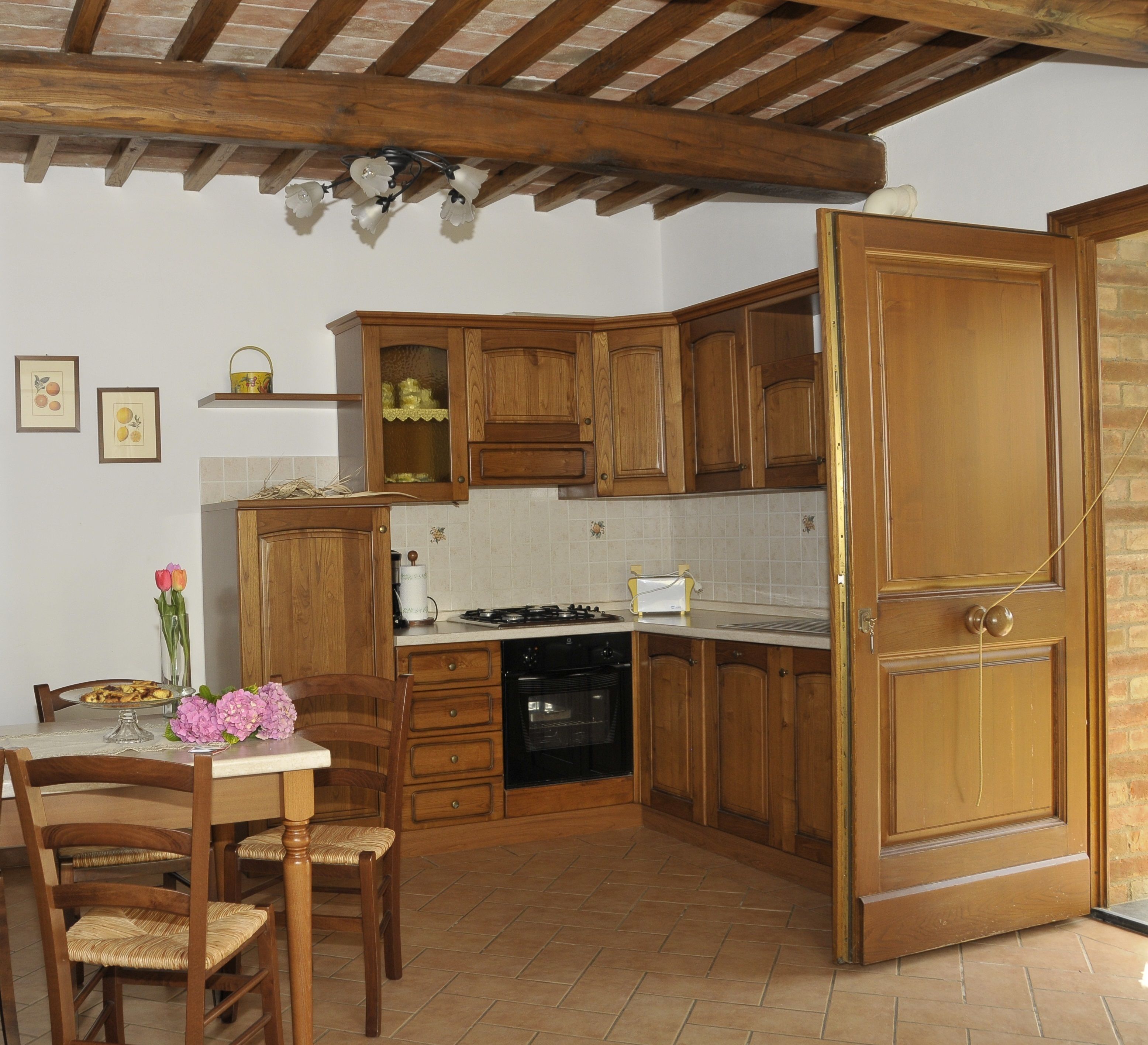 A kitchen with wooden cabinets, a dining table with chairs, a stove, and a dishwasher.