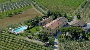 An aerial view of a vineyard with a large building, swimming pool, and surrounding greenery. - Agriturismo Renai e Monte (Gambassi Terme)