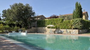 A swimming pool with lounge chairs and umbrellas, surrounded by stone walls and greenery. - Agriturismo Renai e Monte (Gambassi Terme)