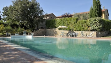 Una piscina al aire libre, sombrillas, tumbonas