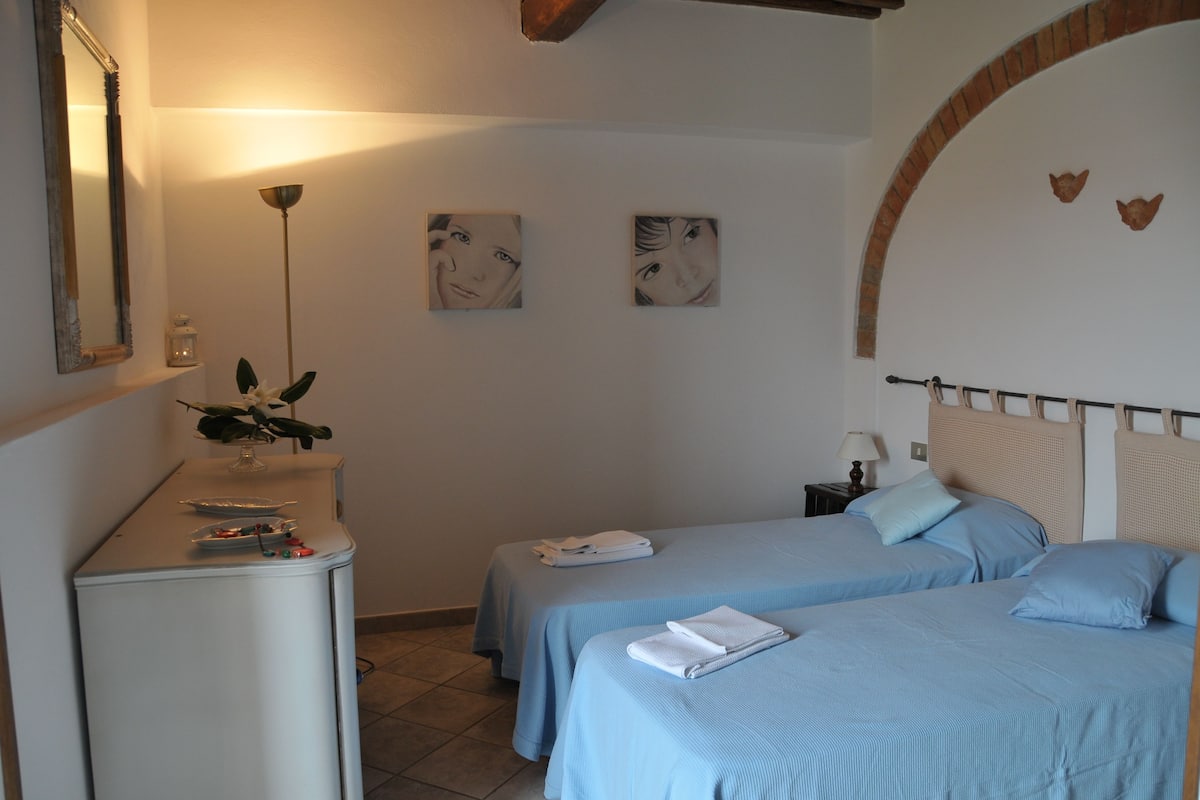 Una habitación de hotel con dos camas, un escritorio, un espejo y una planta.