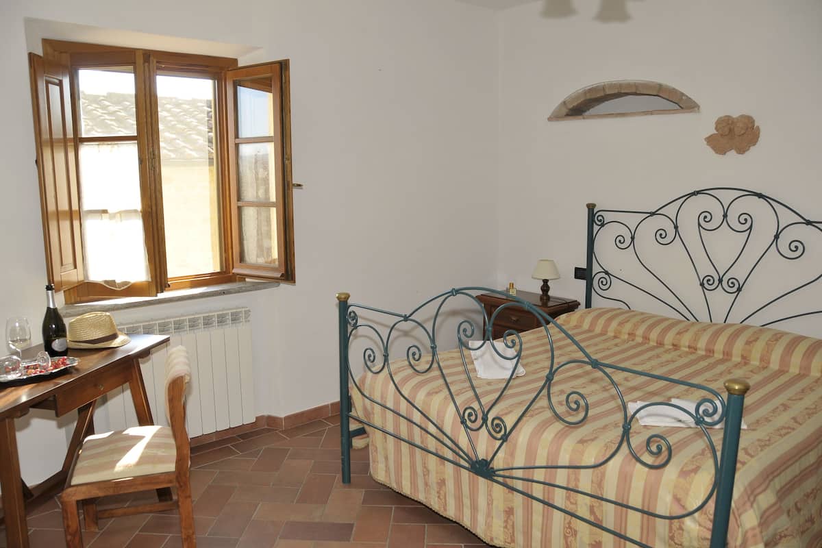 Un dormitorio con cama, ventana, escritorio y silla.