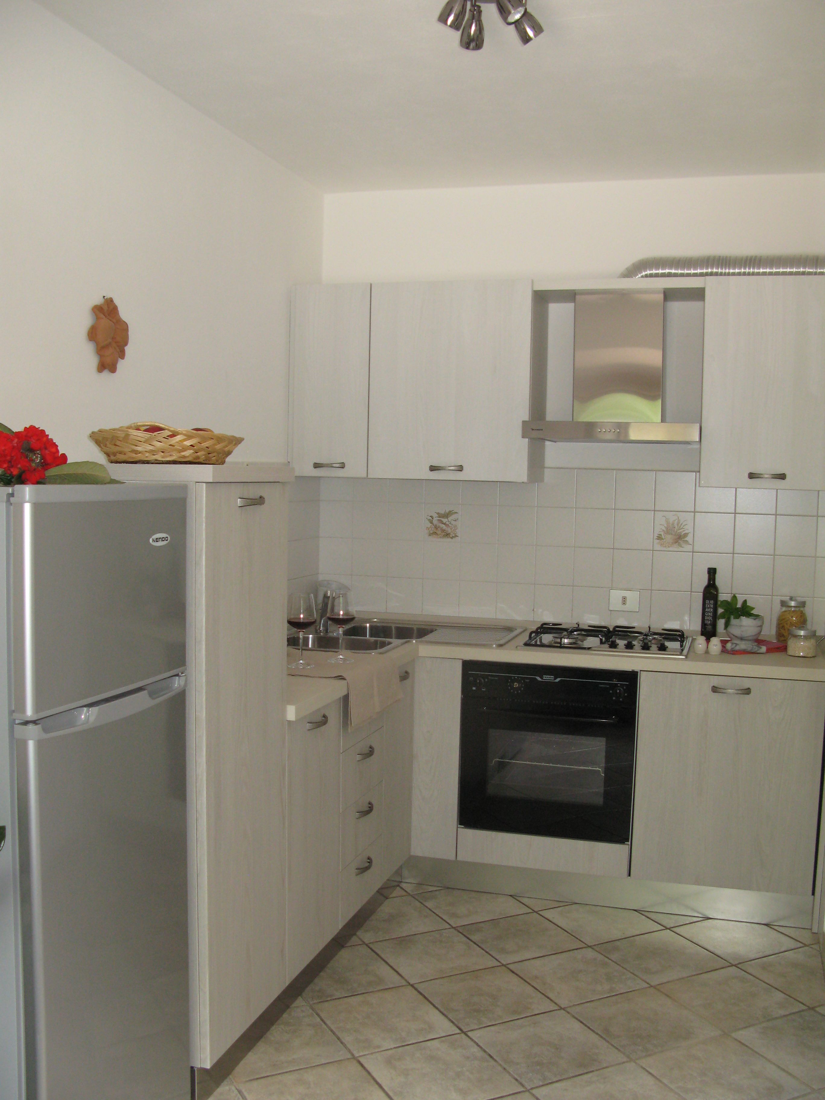 A compact kitchen with a refrigerator, stove, oven, and a sink.