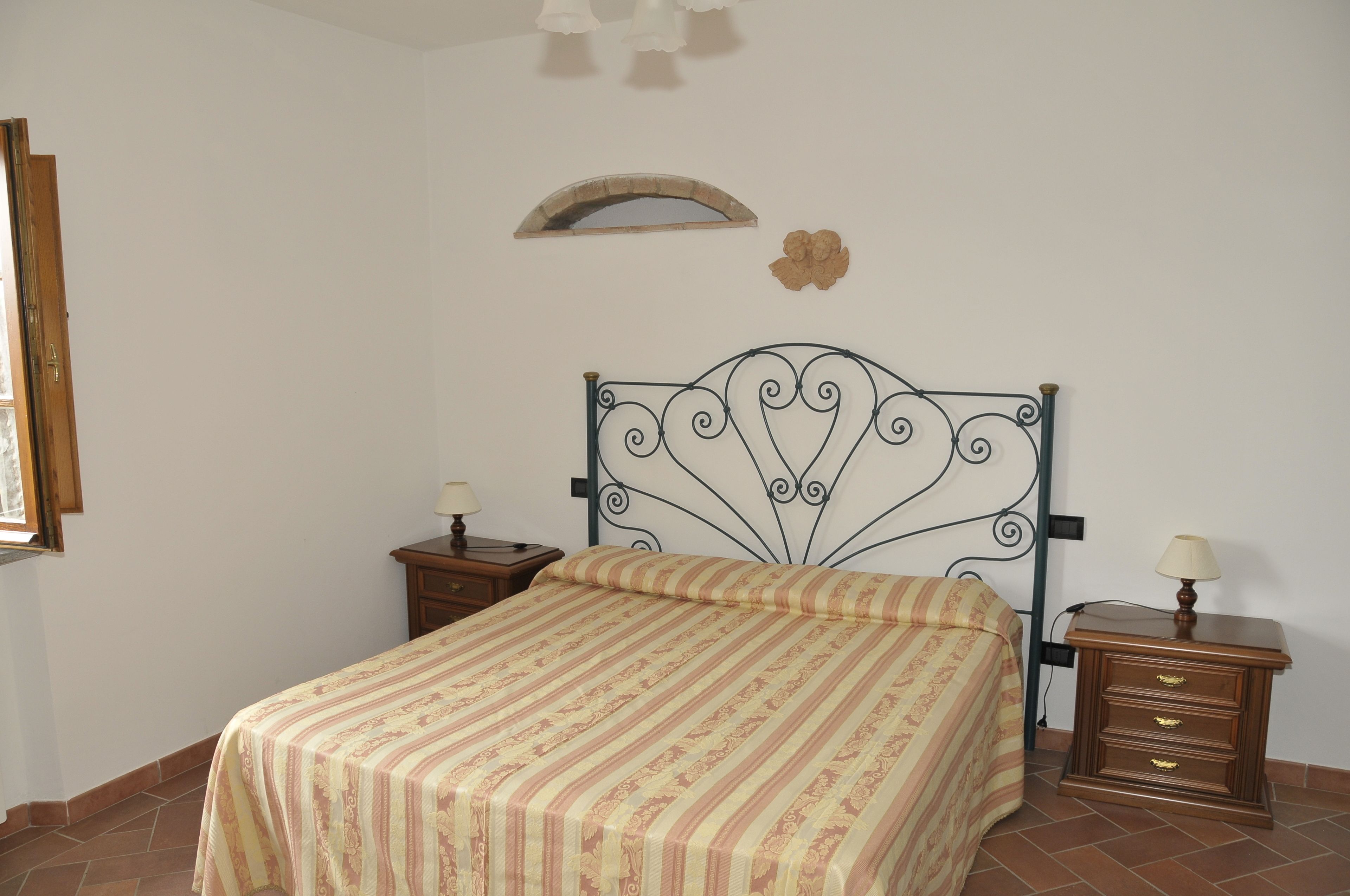 Un dormitorio con cama, dos mesitas de noche, una mesilla auxiliar, un espejo en la pared y un adorno mural.