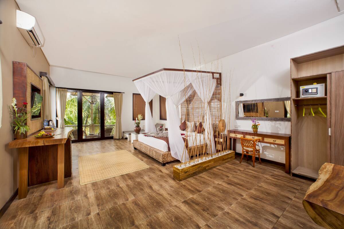A bedroom with a four-poster bed, a desk, a chair, and a small table with a plant.