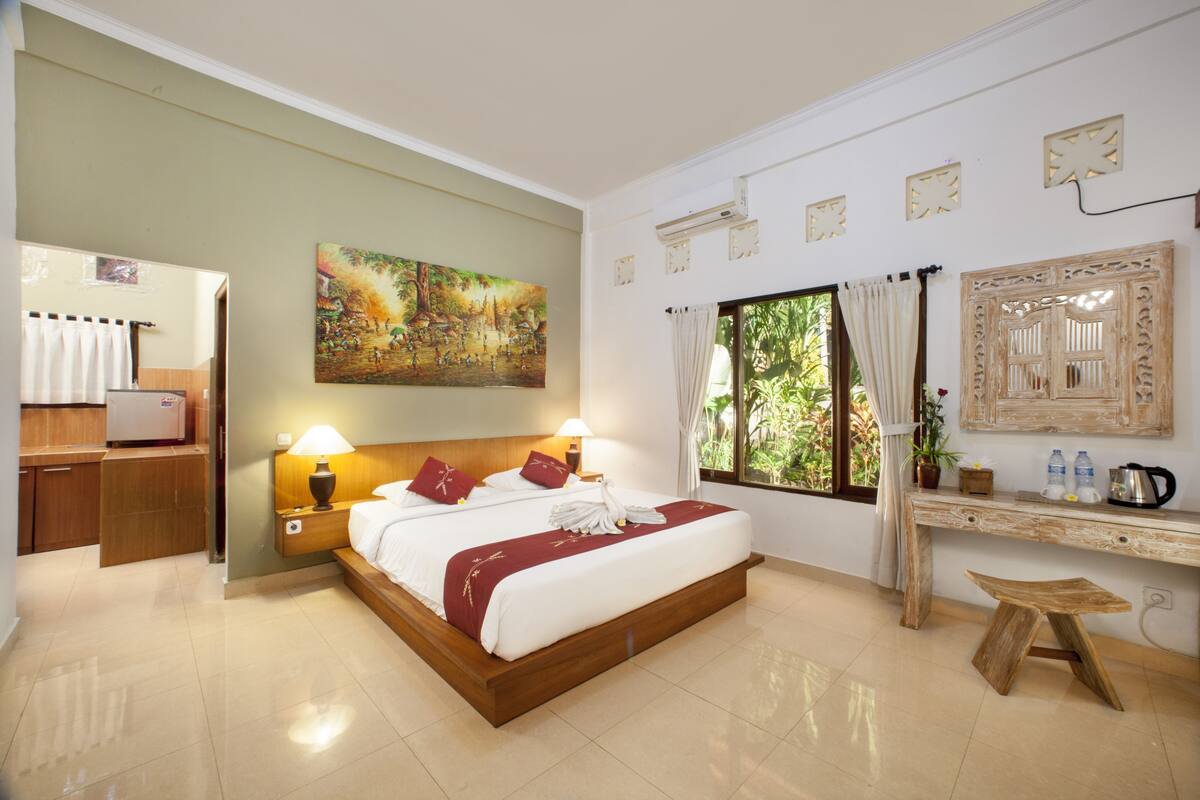 A hotel room with a bed, bedside lamps, a desk, a mirror, and a window with curtains.