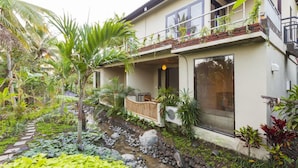 A two-story house with a balcony, surrounded by lush greenery and a small water feature. - Arimba Resort Ubud (Ubud)