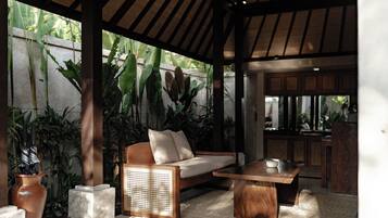 A covered outdoor seating area with a sofa, table, and potted plants.