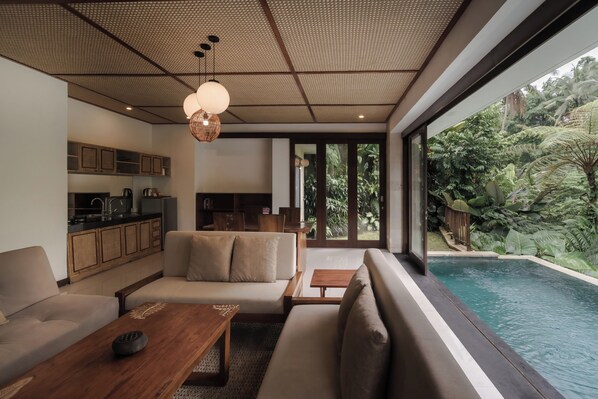 A modern living room with a sofa, coffee table, and a view of a swimming pool.