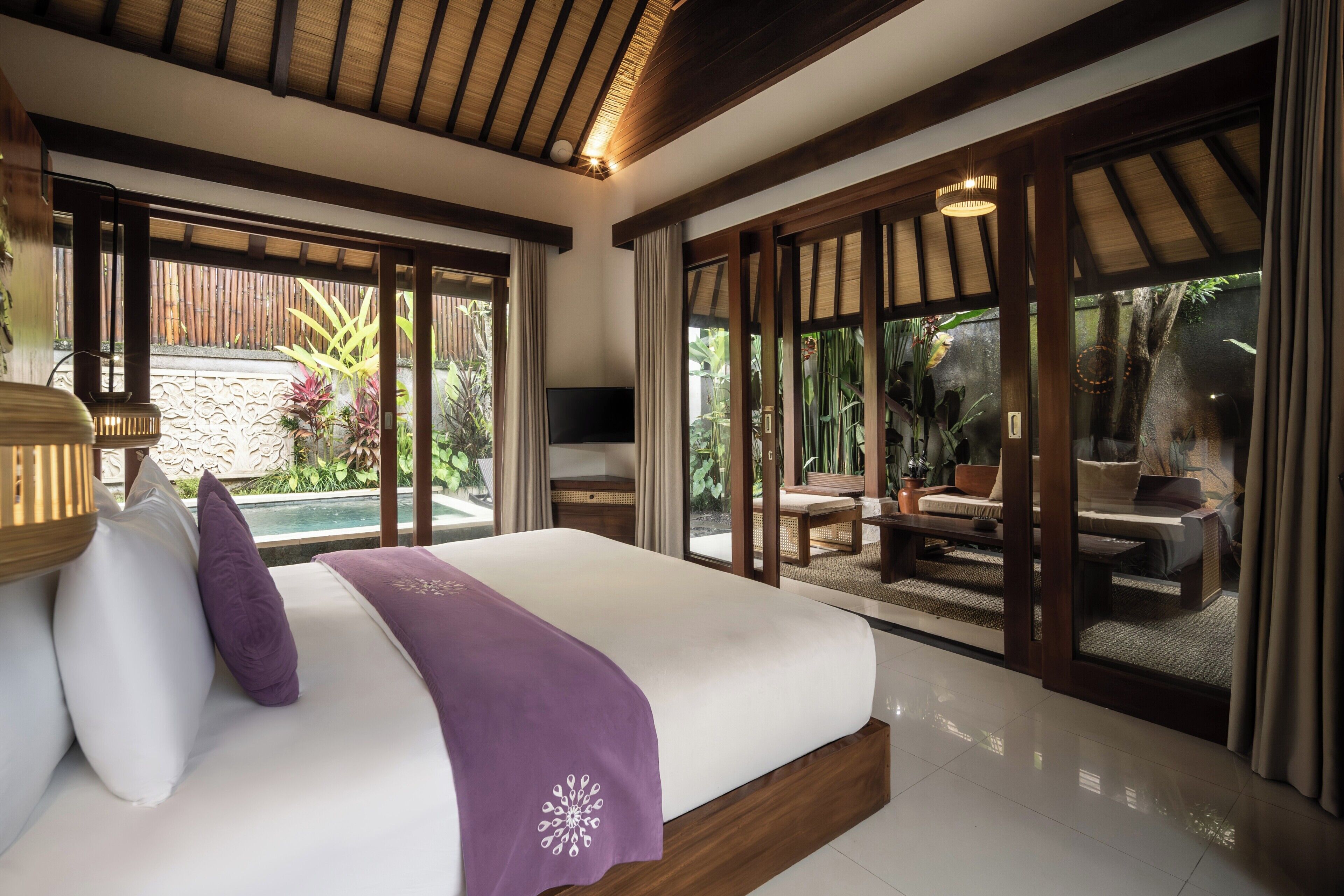 Un dormitorio con una cama grande, un televisor y vistas a una zona de estar exterior.