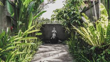 Um caminho que leva a uma estátua em um jardim exuberante.