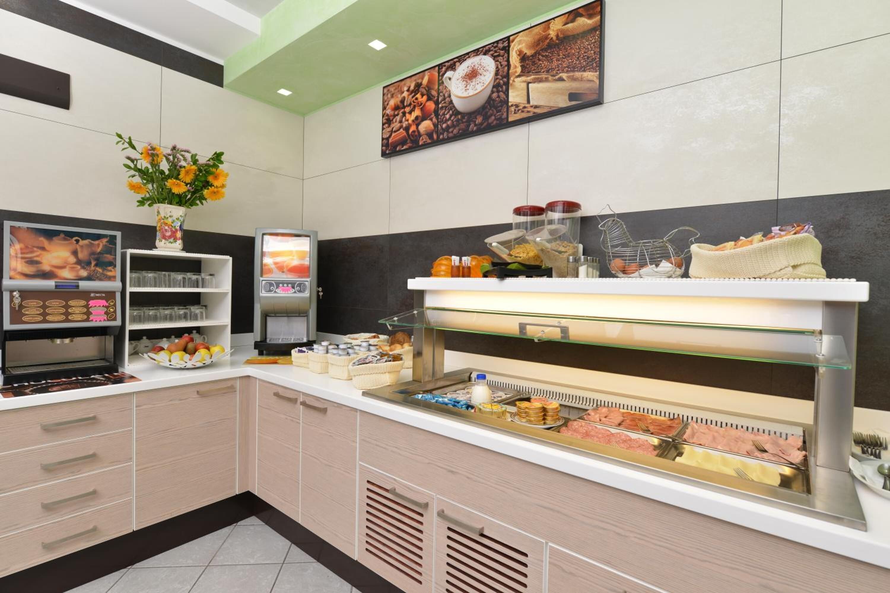 A buffet area with a variety of food options, a coffee station, and a decorative vase with flowers.