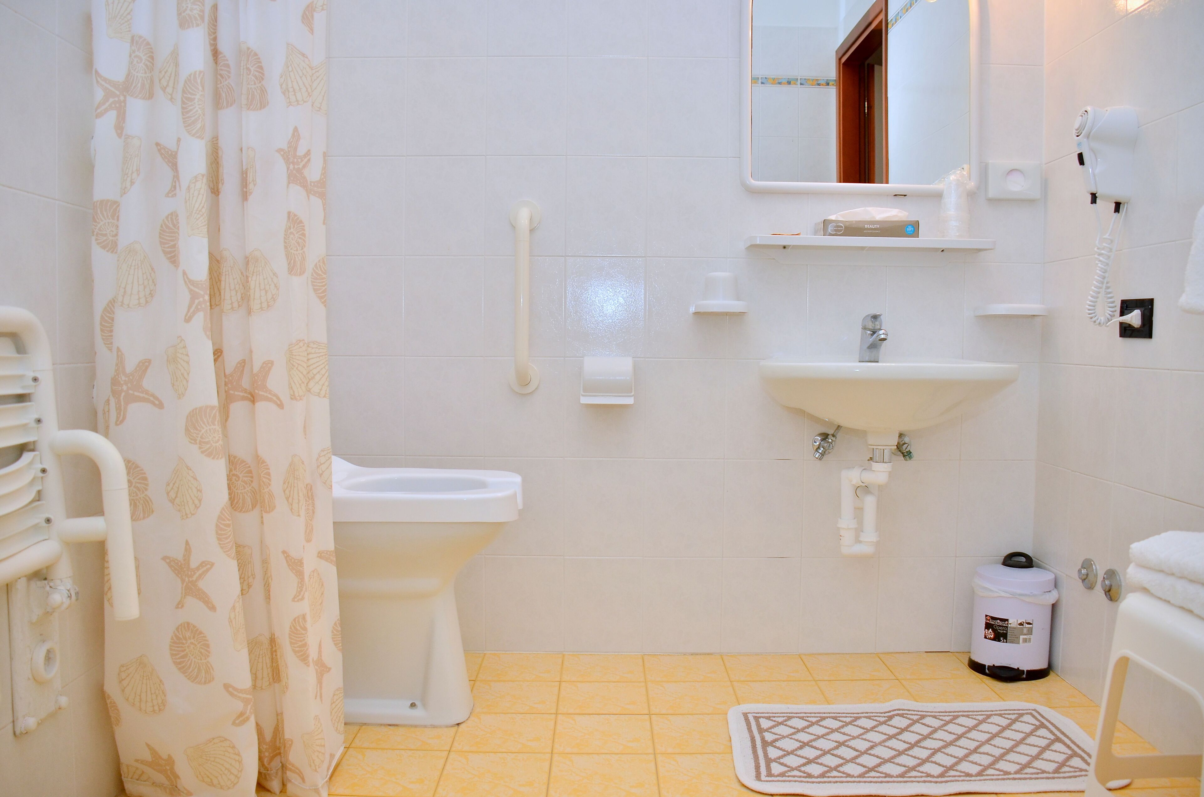A bathroom with a toilet, sink, shower curtain, and a hand dryer.